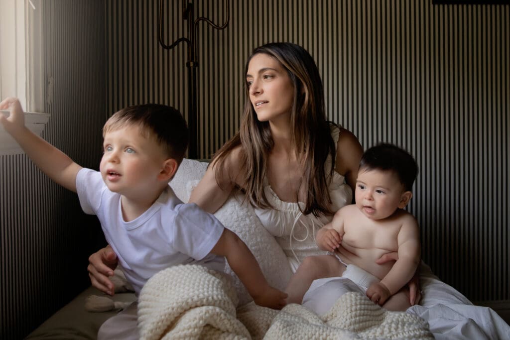 Mother with two sons at home sitting on the sofa next to the window spending quality time.