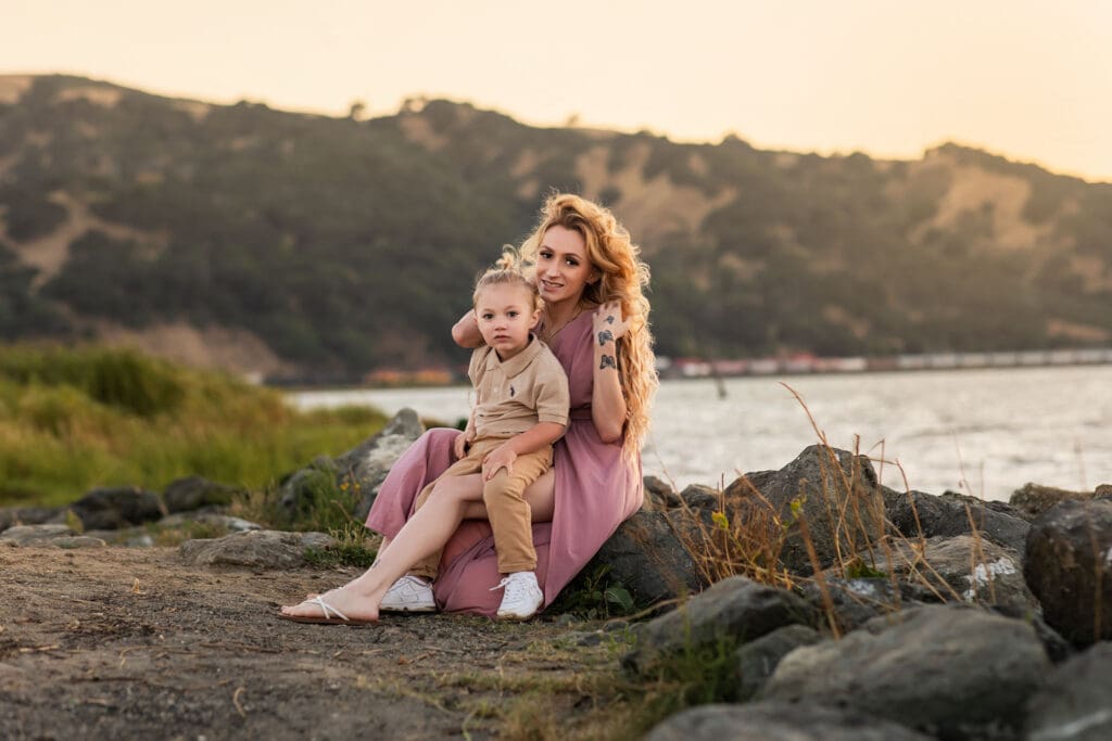 Mother with her son posing for a bay area photographer near a Martinez shoreline for her Outdoor Maternity Photography